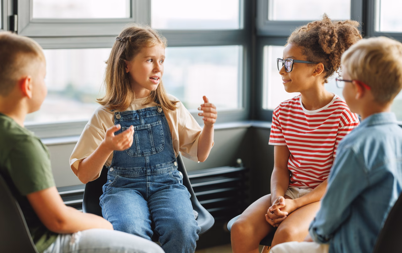 Children in a classroom talk to each other.